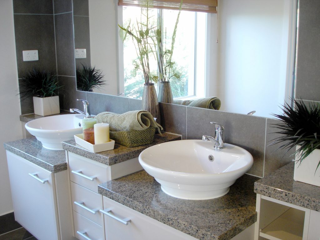 A bathroom vanity with floating sinks and dark gray countertops